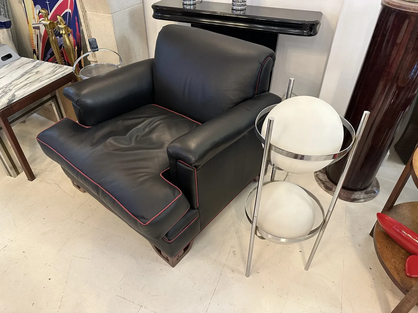 Antique floor lamp with sphere in a stylish setting near a black armchair.