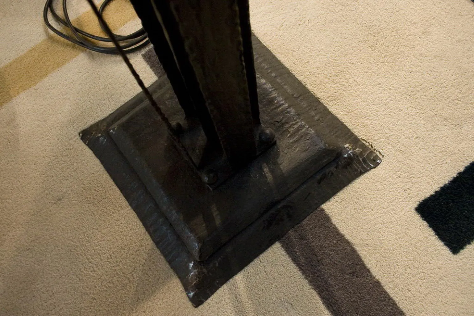Base of an antique floor lamp on a light rug