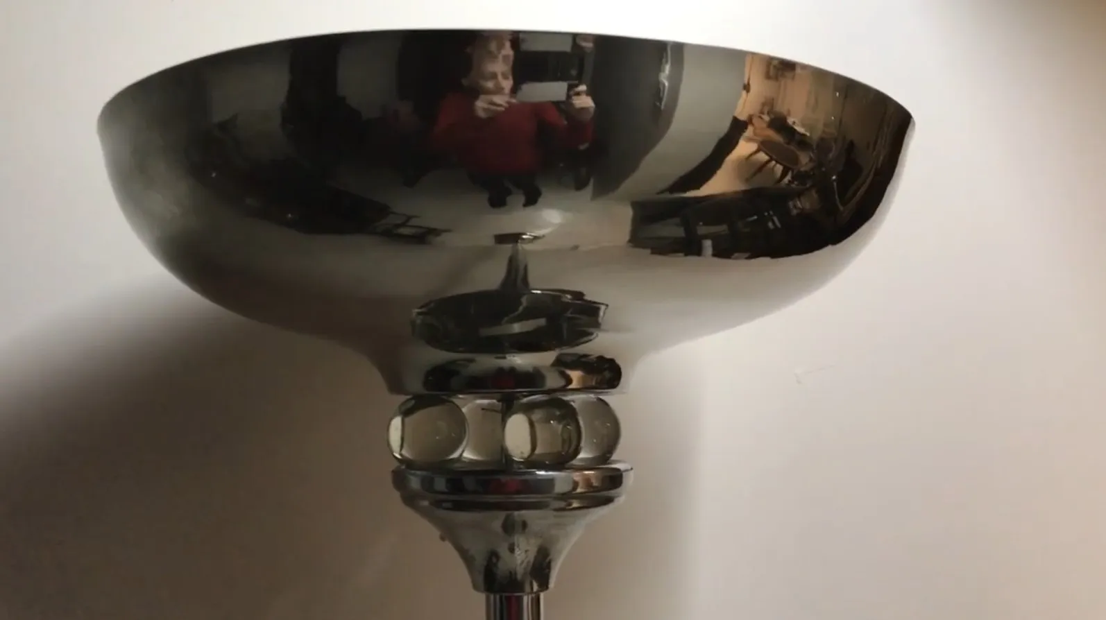 Lampada da terra antica con design elegante e base in vetro, che riflette la luce in modo caldo.