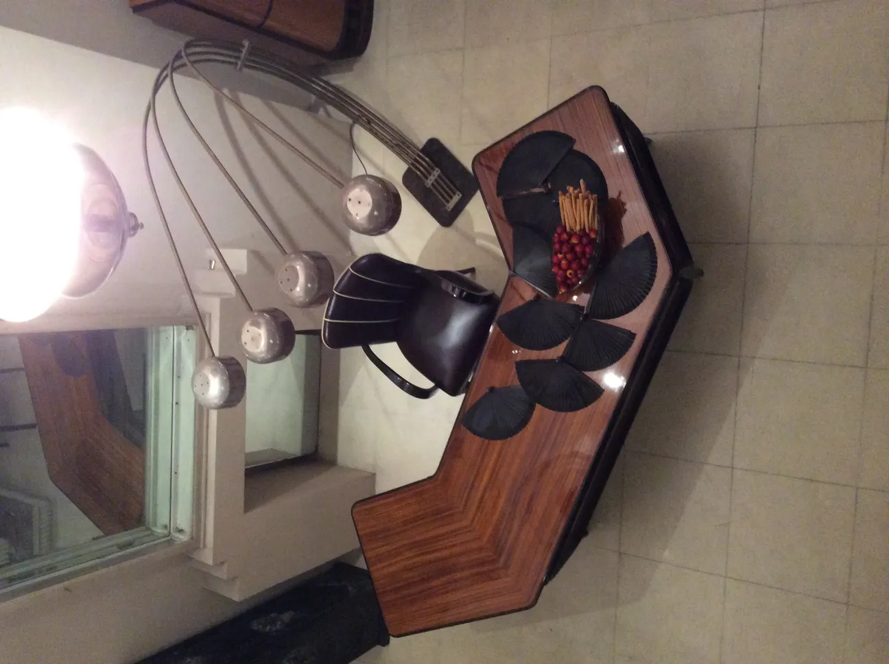 Lámpara de pie antigua con múltiples luces y diseño elegante, silla y mesa al fondo.