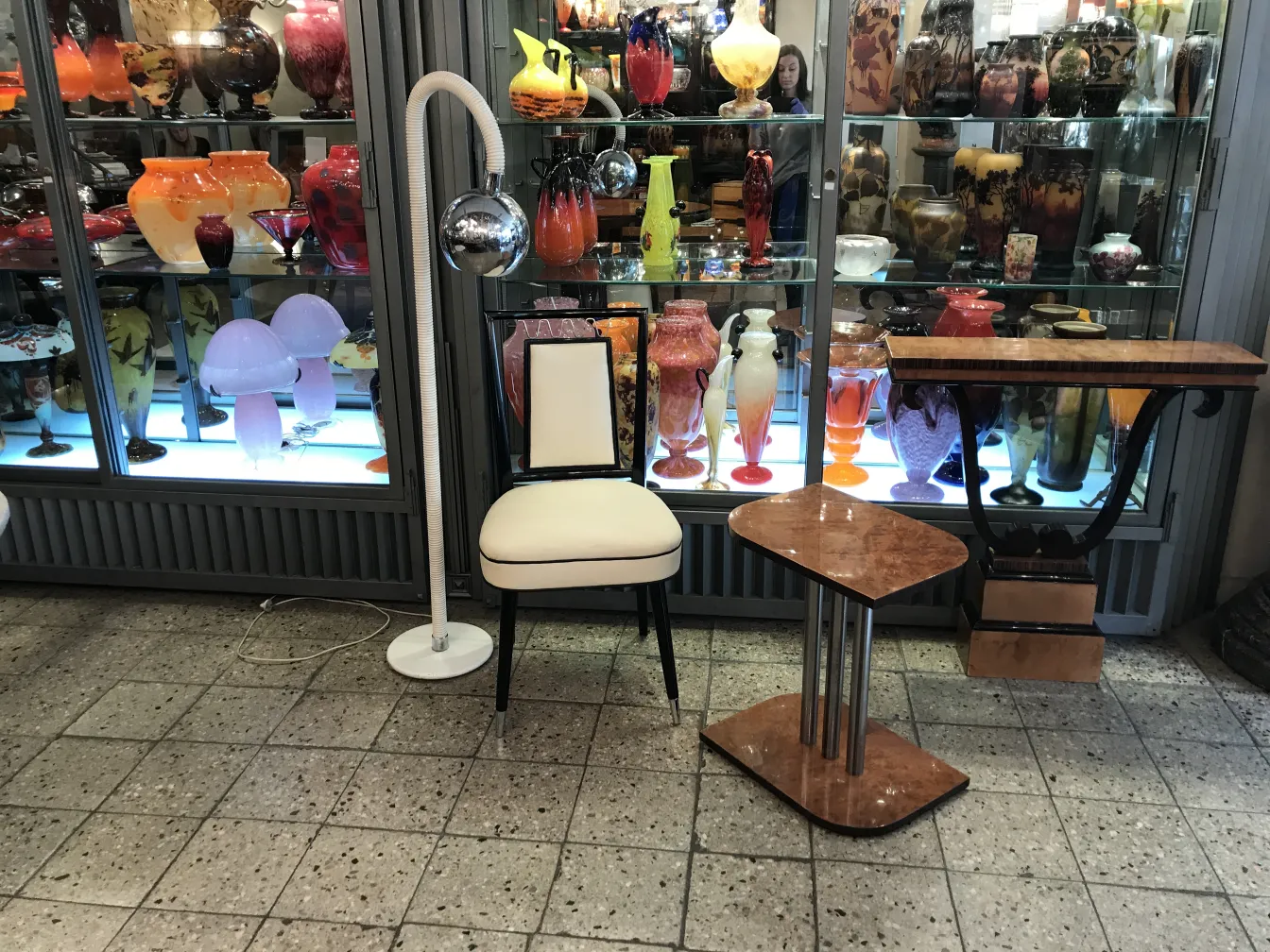 Lampada da terra antica con palla specchiata in un ambiente vintage. Sedia bianca e tavoli decorativi sullo sfondo.