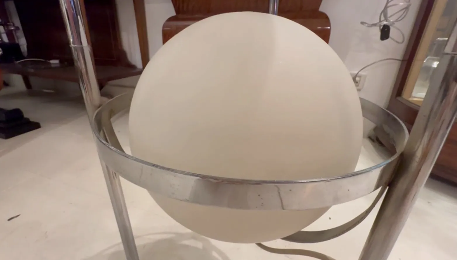 Lampe de sol ancienne avec sphère blanche et base en métal dans un cadre élégant.