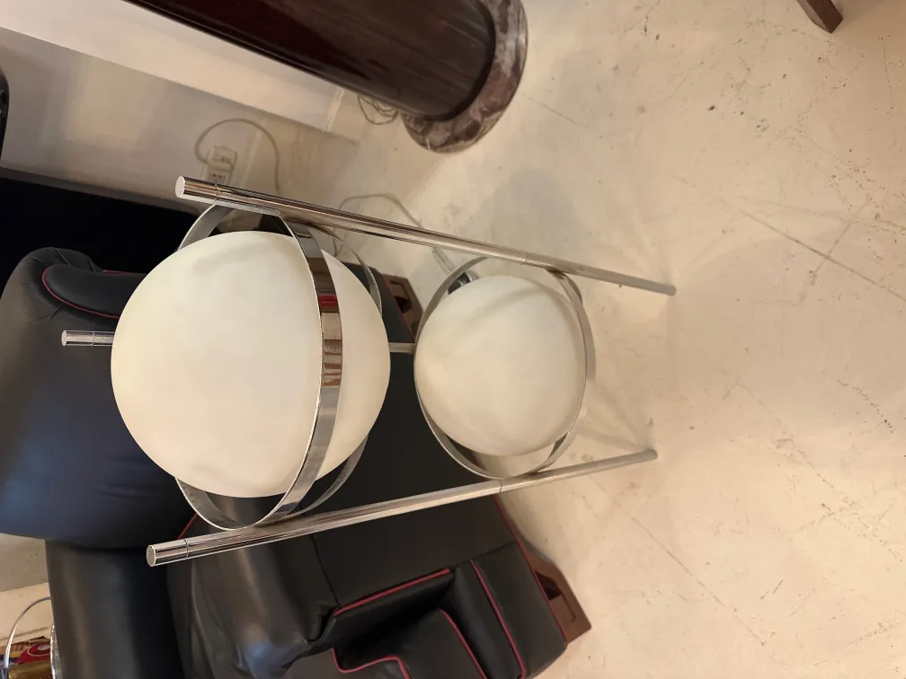 Lampada da terra antica con base in metallo e due sfere bianche, in un ambiente moderno.