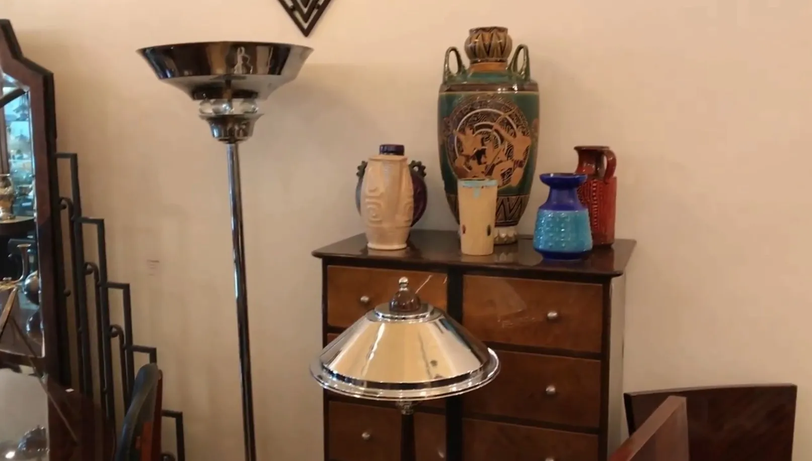 Antique floor lamp with shiny metal shade, surrounded by colorful vases in an elegant setting.