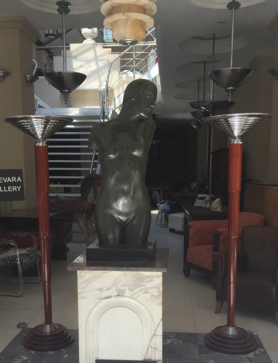 Two antique floor lamps with elegant details next to a sculpture