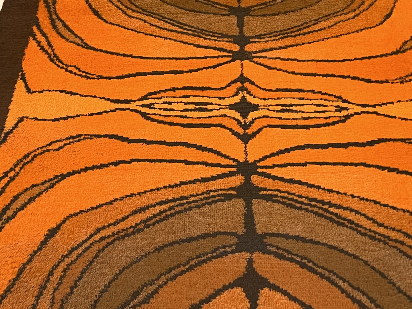 Tapis ancien présentant des motifs géométriques en orange