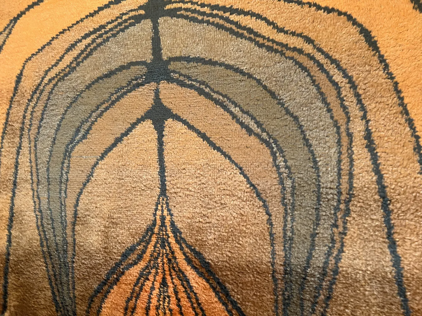 Alfombra antigua con diseño abstracto en tonos marrones y negros.