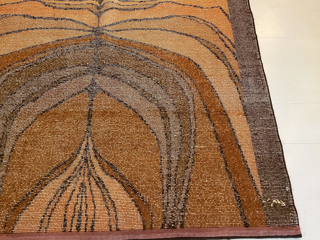 Alfombra antigua con un diseño abstracto en tonos cálidos, en un ambiente elegante