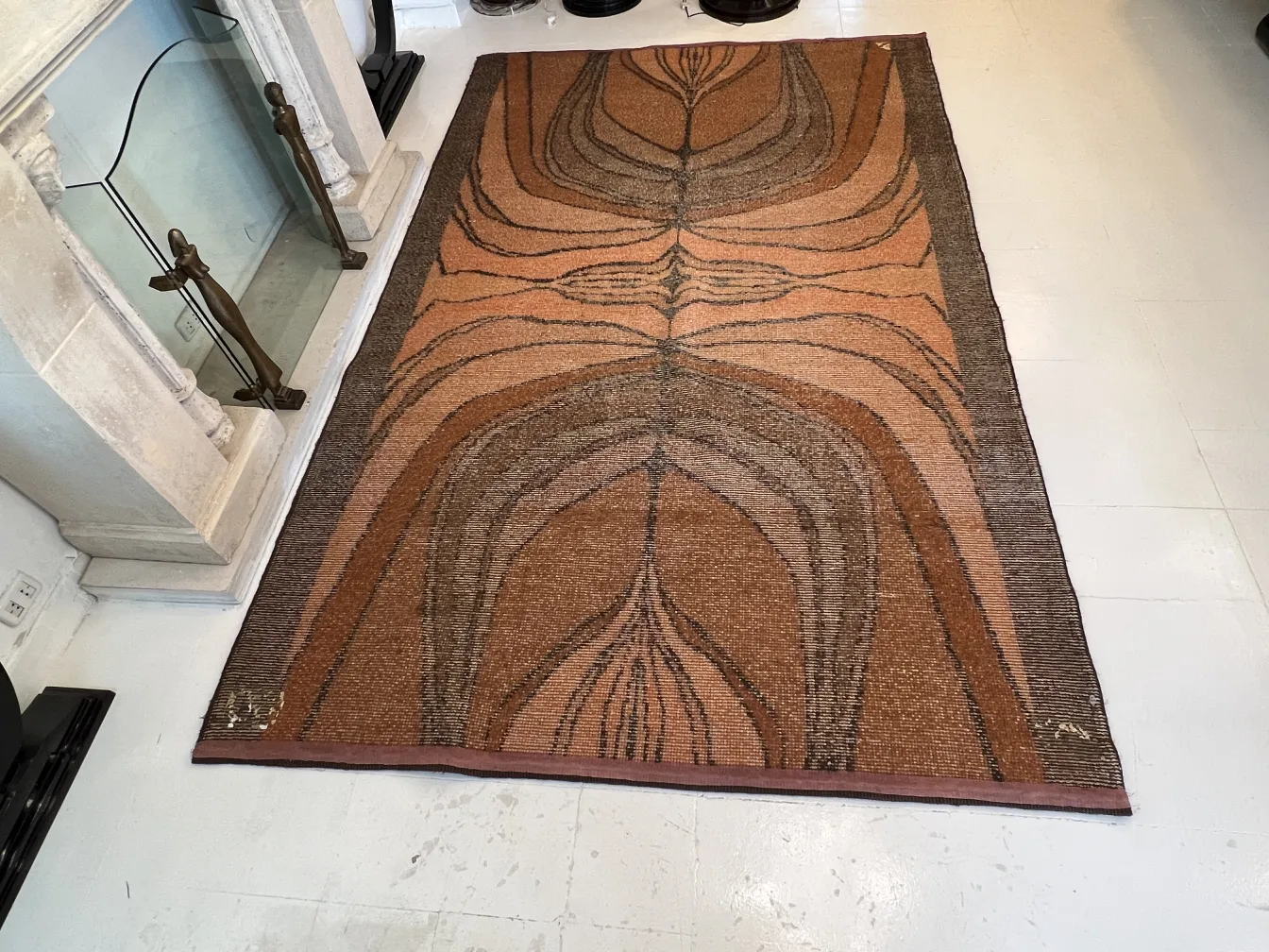 Antiker Teppich mit organischem Design in Brauntönen und Beige, in einer gemütlichen Umgebung.