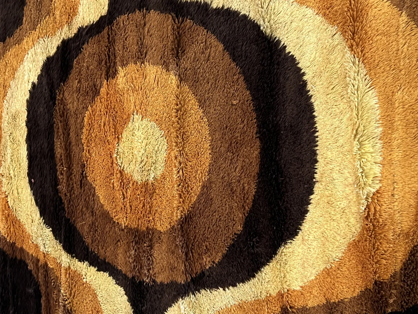 Antique carpet featuring brown tones and circular patterns