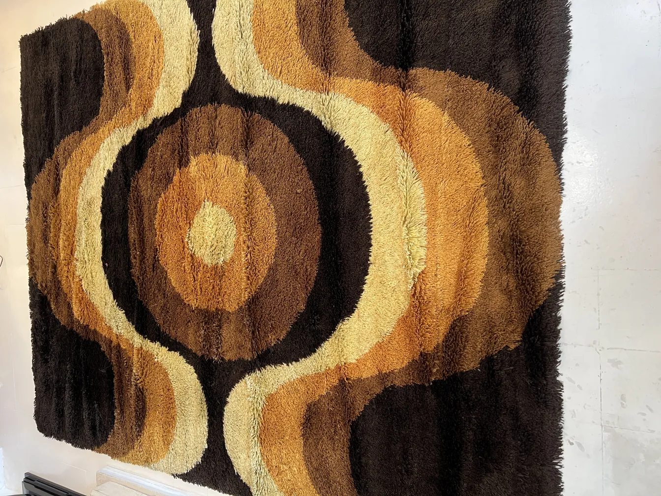 alfombra antigua en tonos marrones y beige, con patrones circulares