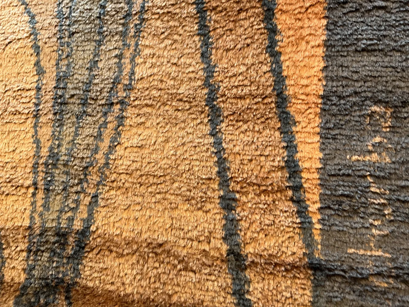 Alfombra antigua con textura acolchada en tonos cálidos.