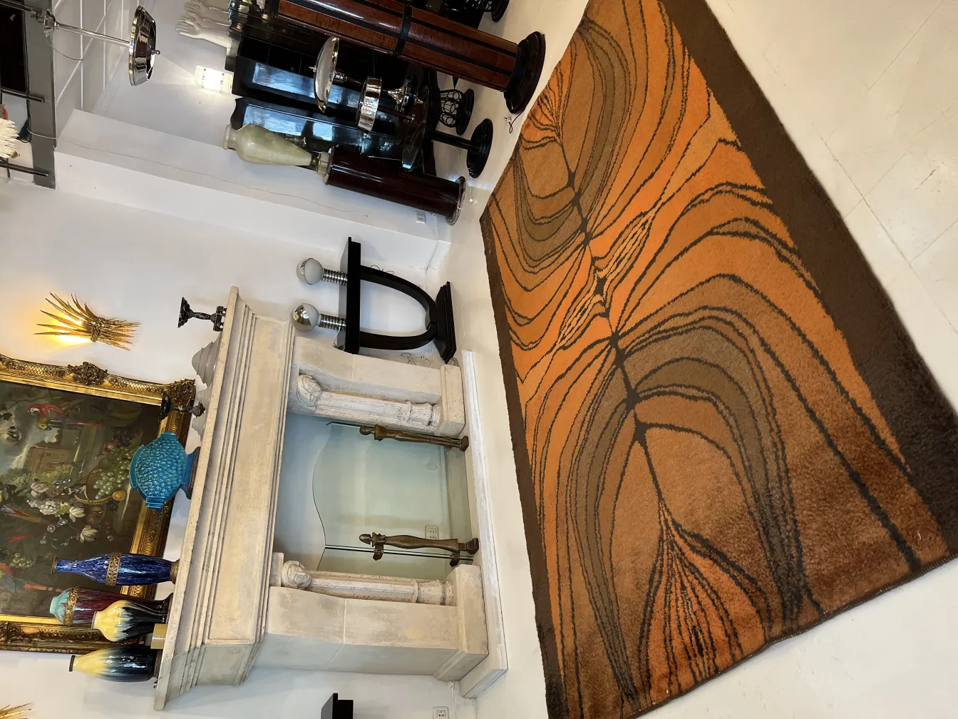 Tapis ancien avec des motifs oranges et bruns, dans un environnement décoratif