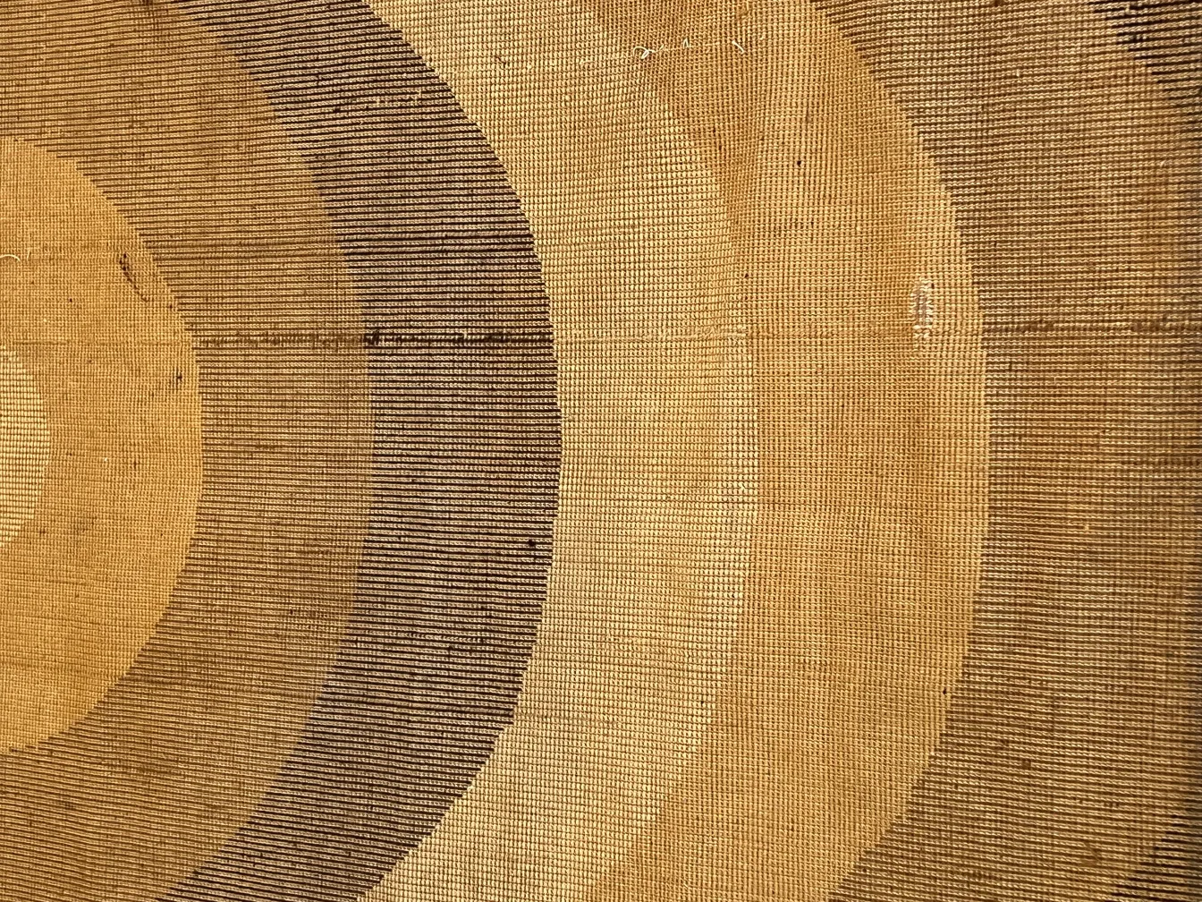 Tapis ancien avec des motifs circulaires dans des tons chauds, textures rustiques pour la décoration.