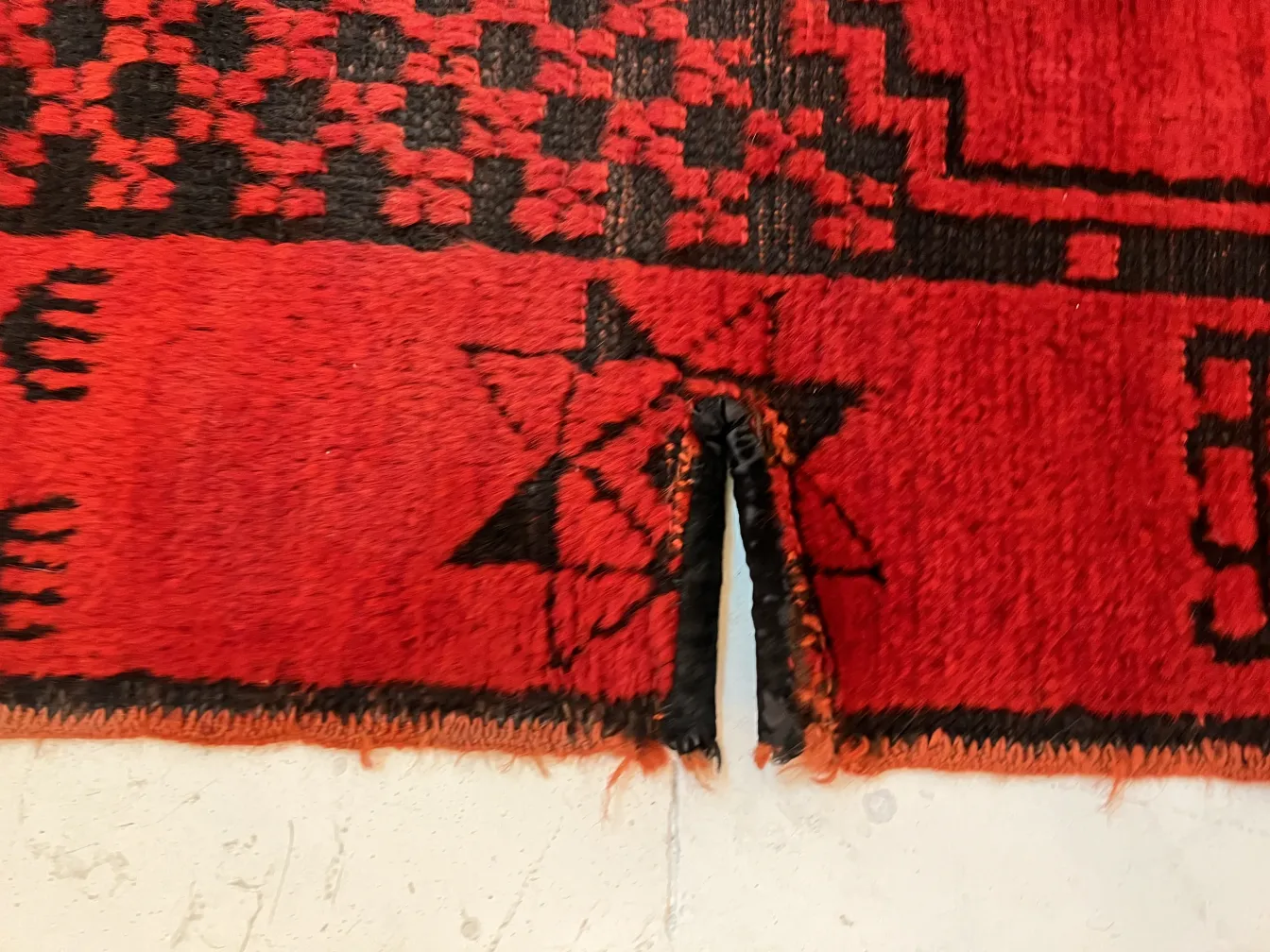 alfombra antigua roja con símbolos en negro, detalle