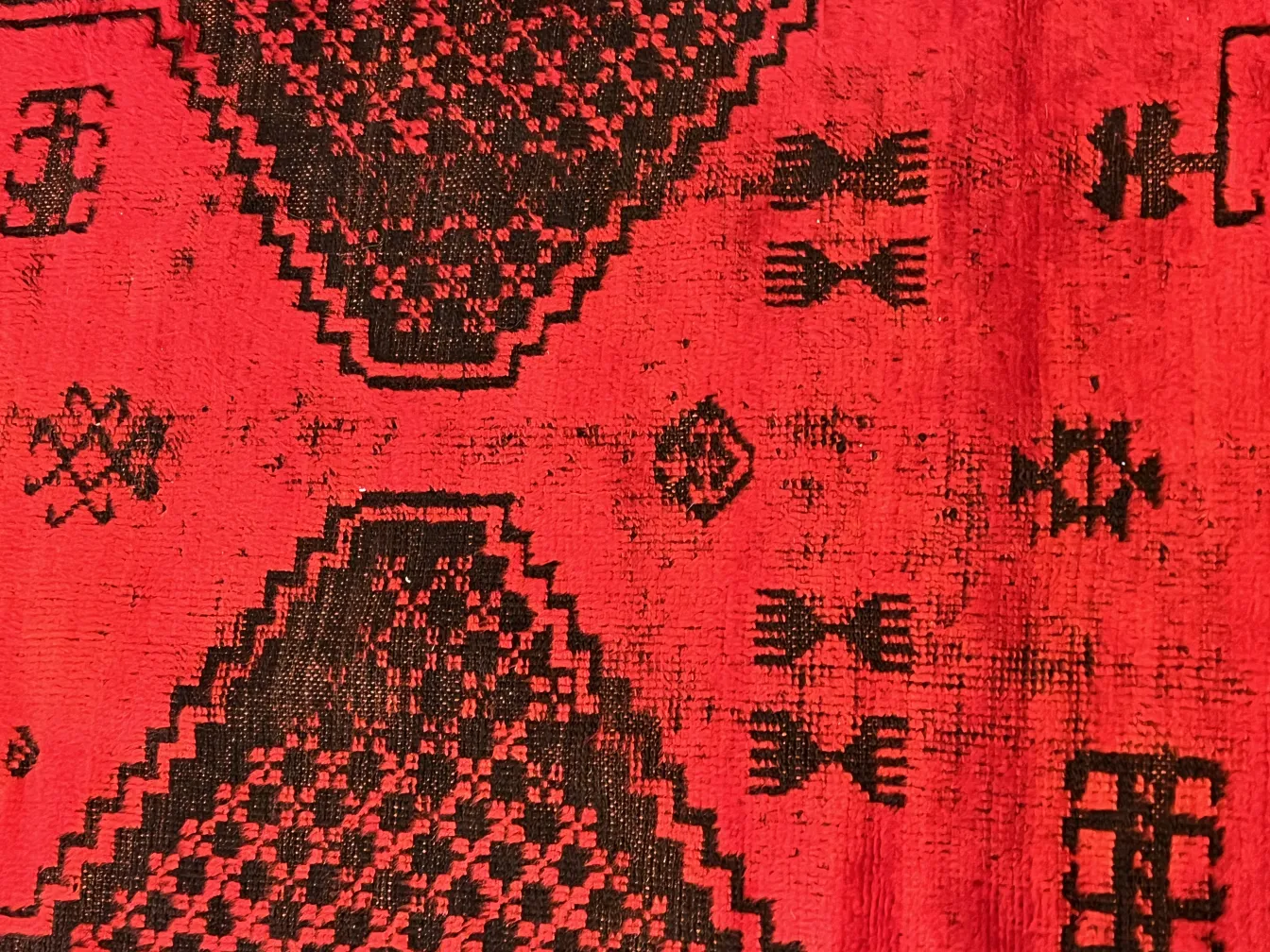 alter roter Teppich mit schwarzen Mustern und geometrischem Design