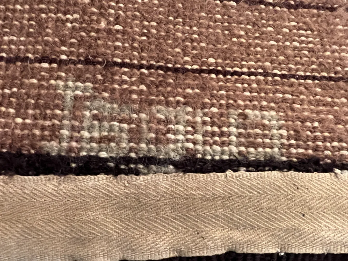 Tapis ancien avec design artisanal en tons bruns.