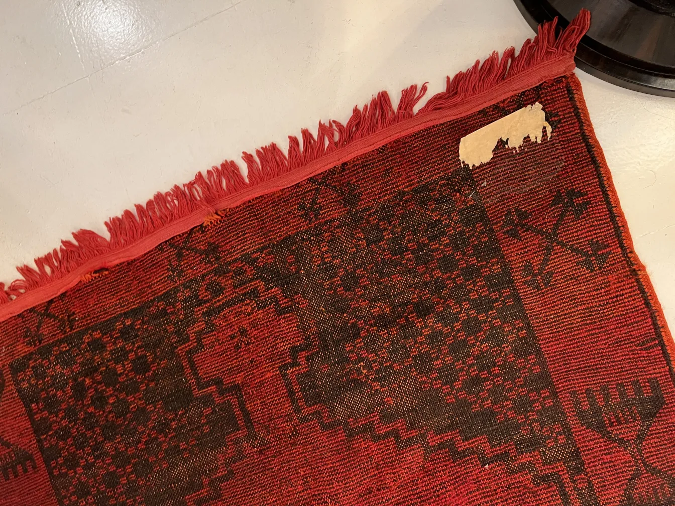 antique carpet with fringes, red and black design