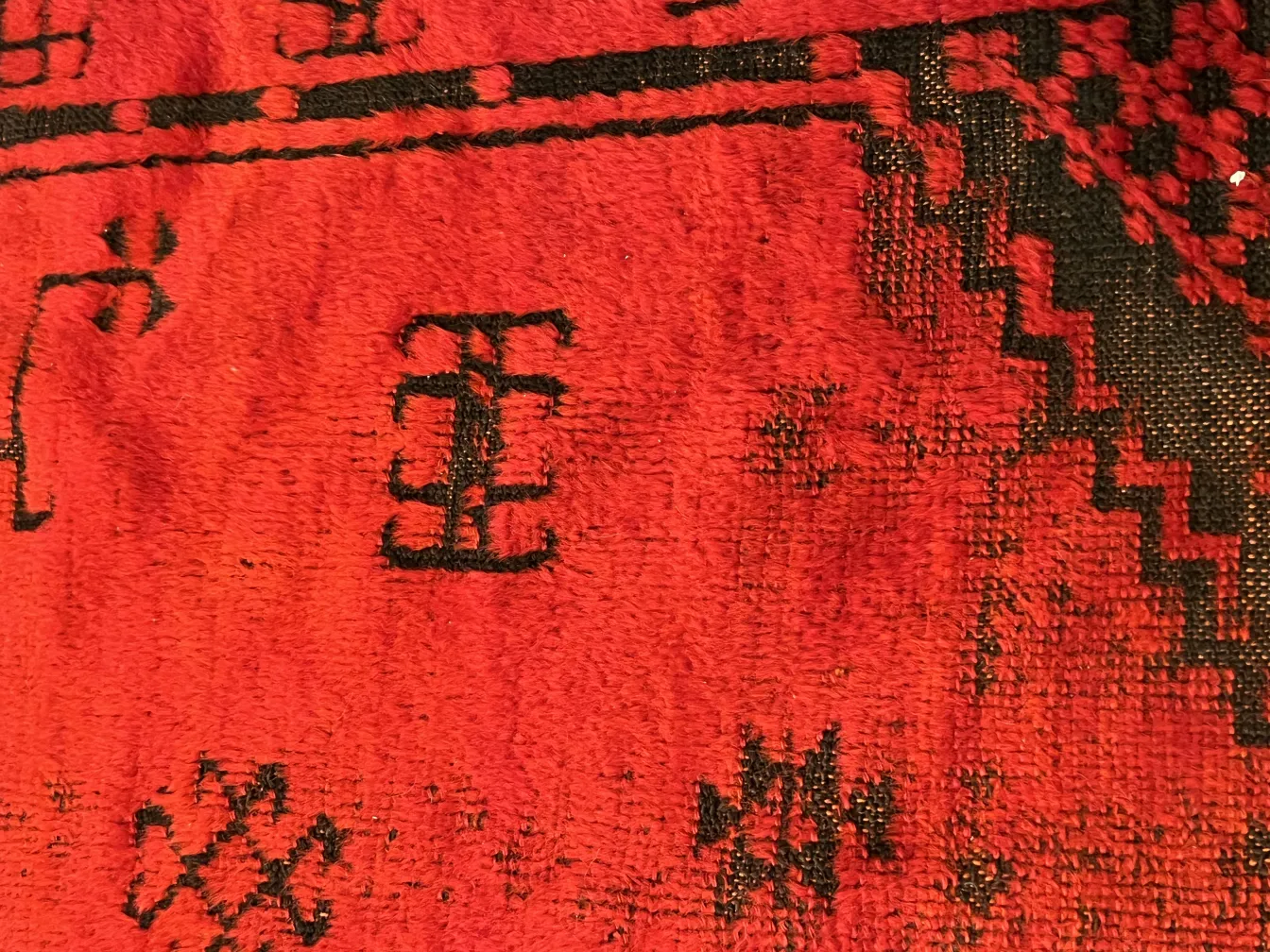 Tapis ancien rouge avec détails noirs