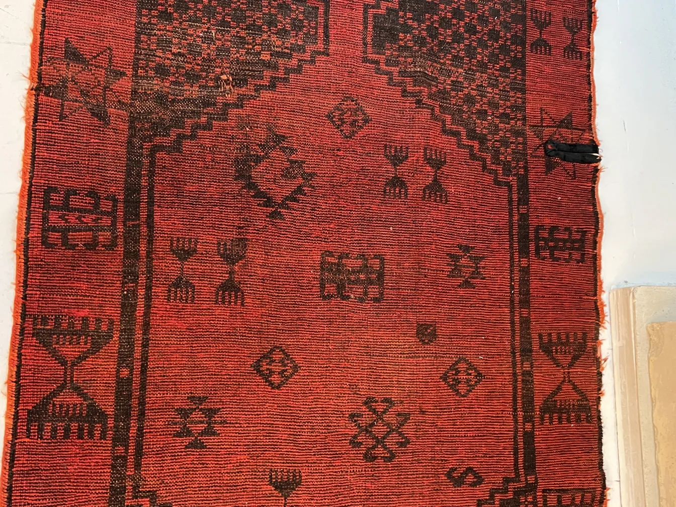 Antique red carpet with black decorative patterns.