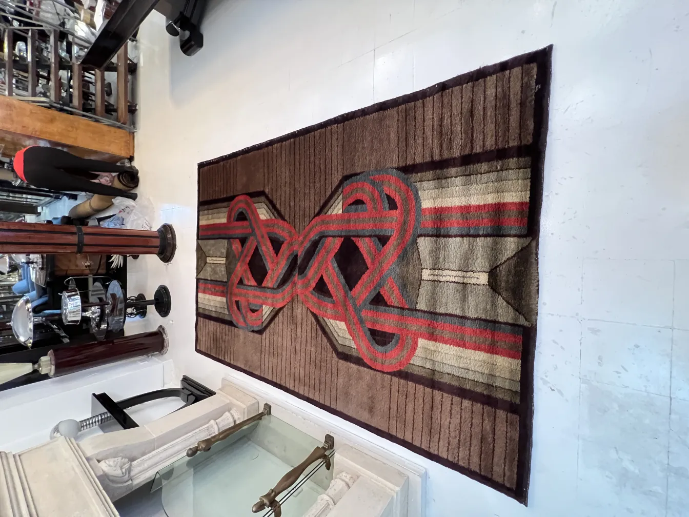 Tapis ancien avec des motifs géométriques en tons de marron et rouge, dans un cadre élégant et classique.