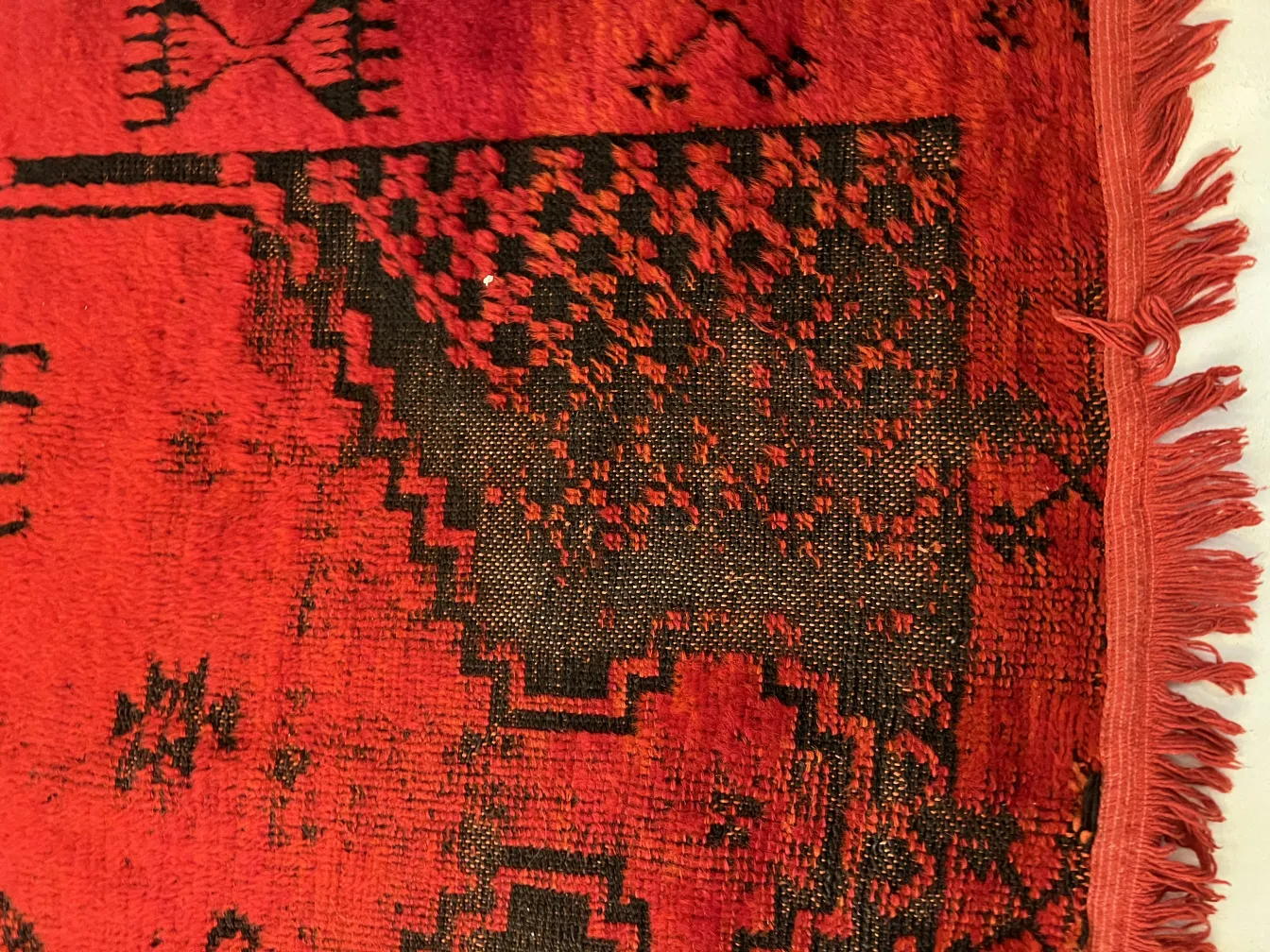 alfombra antigua con diseño en tonos rojos y negros, decorativa