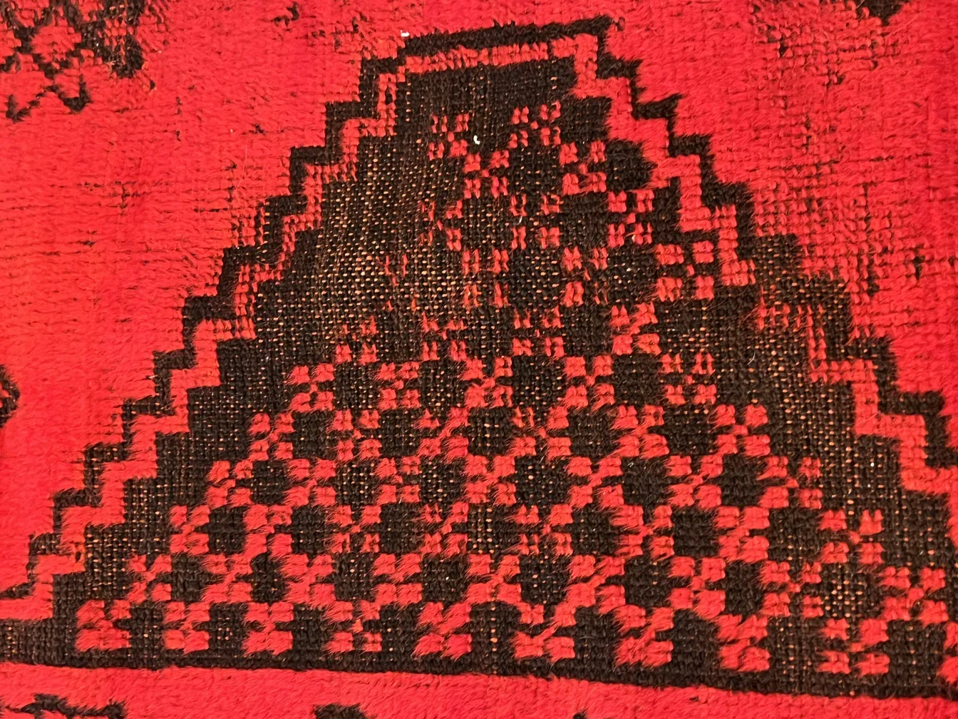 Detalle de una alfombra antigua en rojo y negro con diseño geométrico