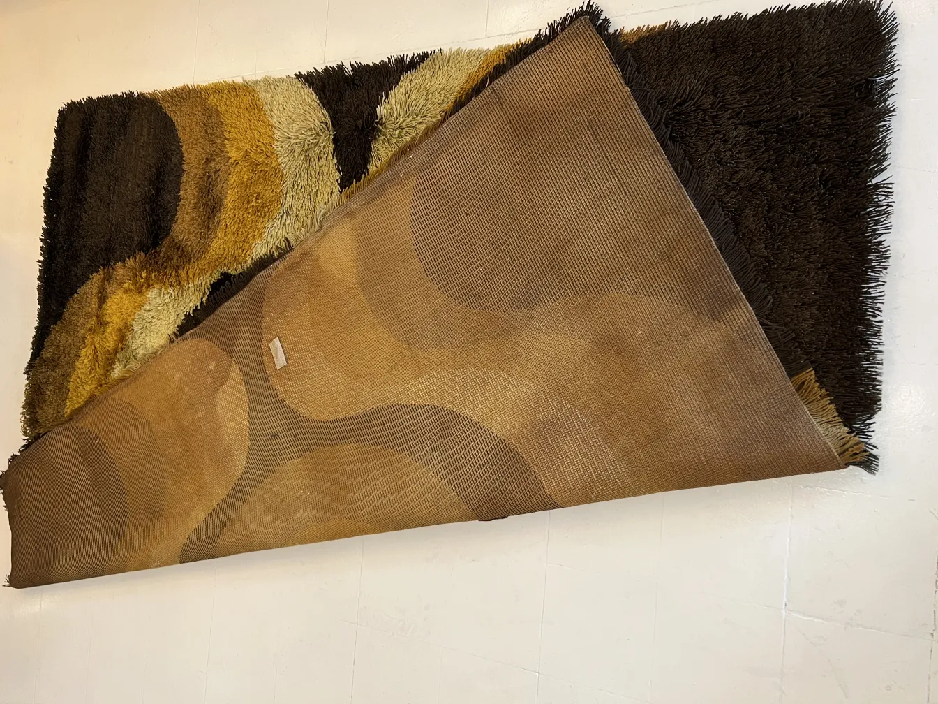 Antique carpet featuring colorful patterns in shades of brown and yellow.