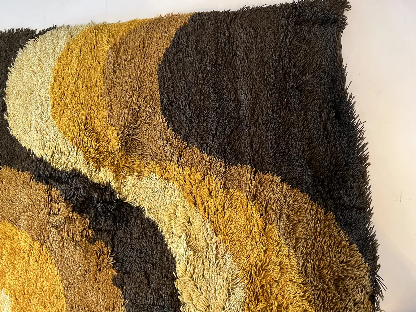 tapis ancien avec des couleurs brunes et jaunes dans un design ondulé