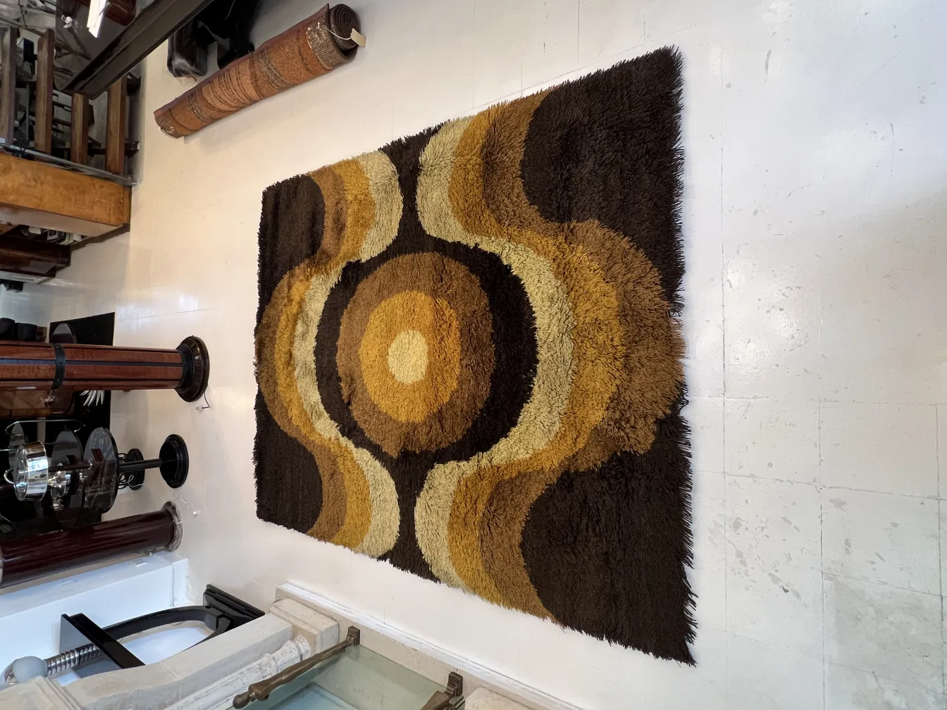 Tapis ancien avec motif géométrique en tons de marron et jaune dans un environnement classique.