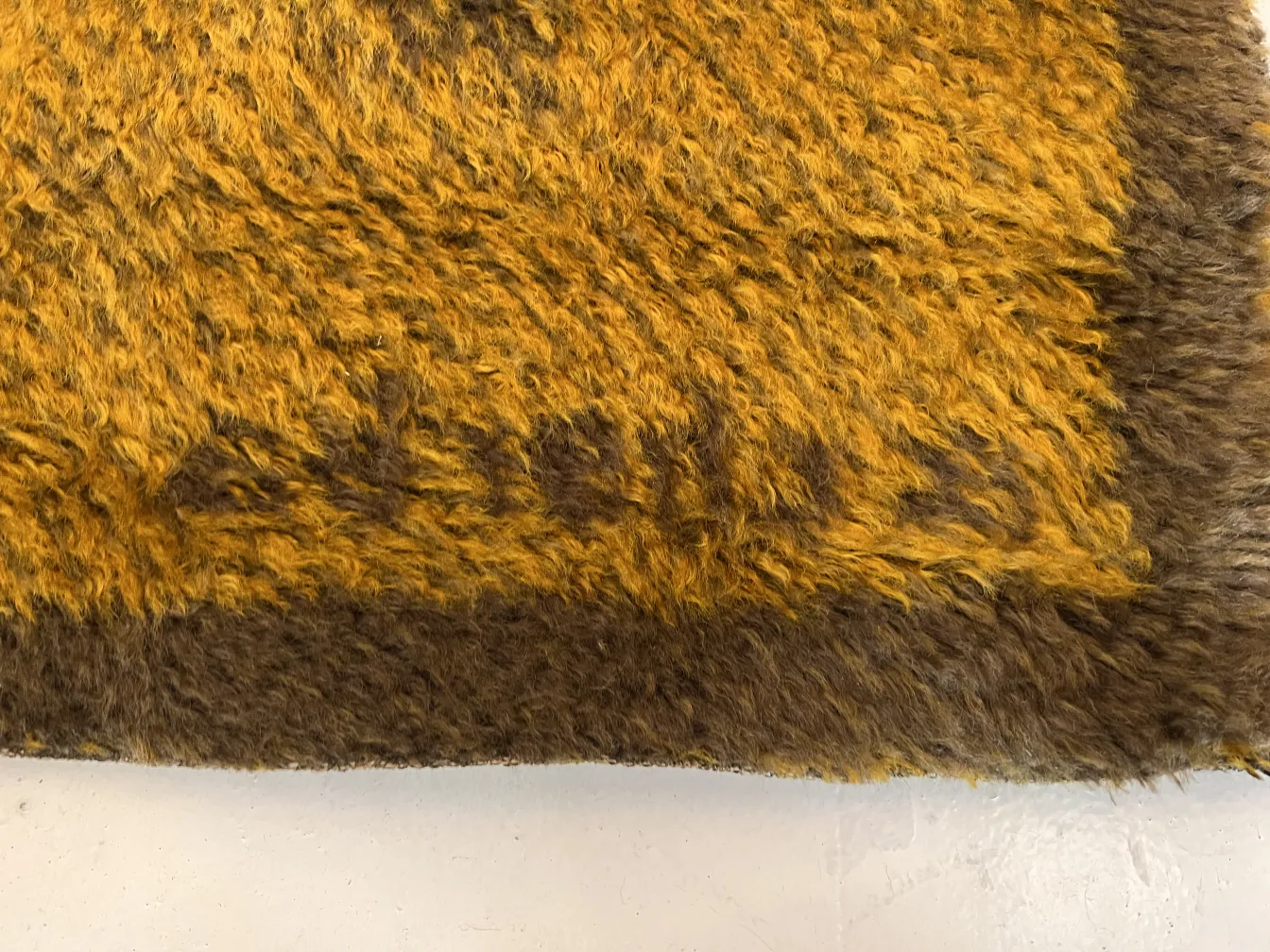 Alfombra antigua con tonos amarillos suaves y textura esponjosa