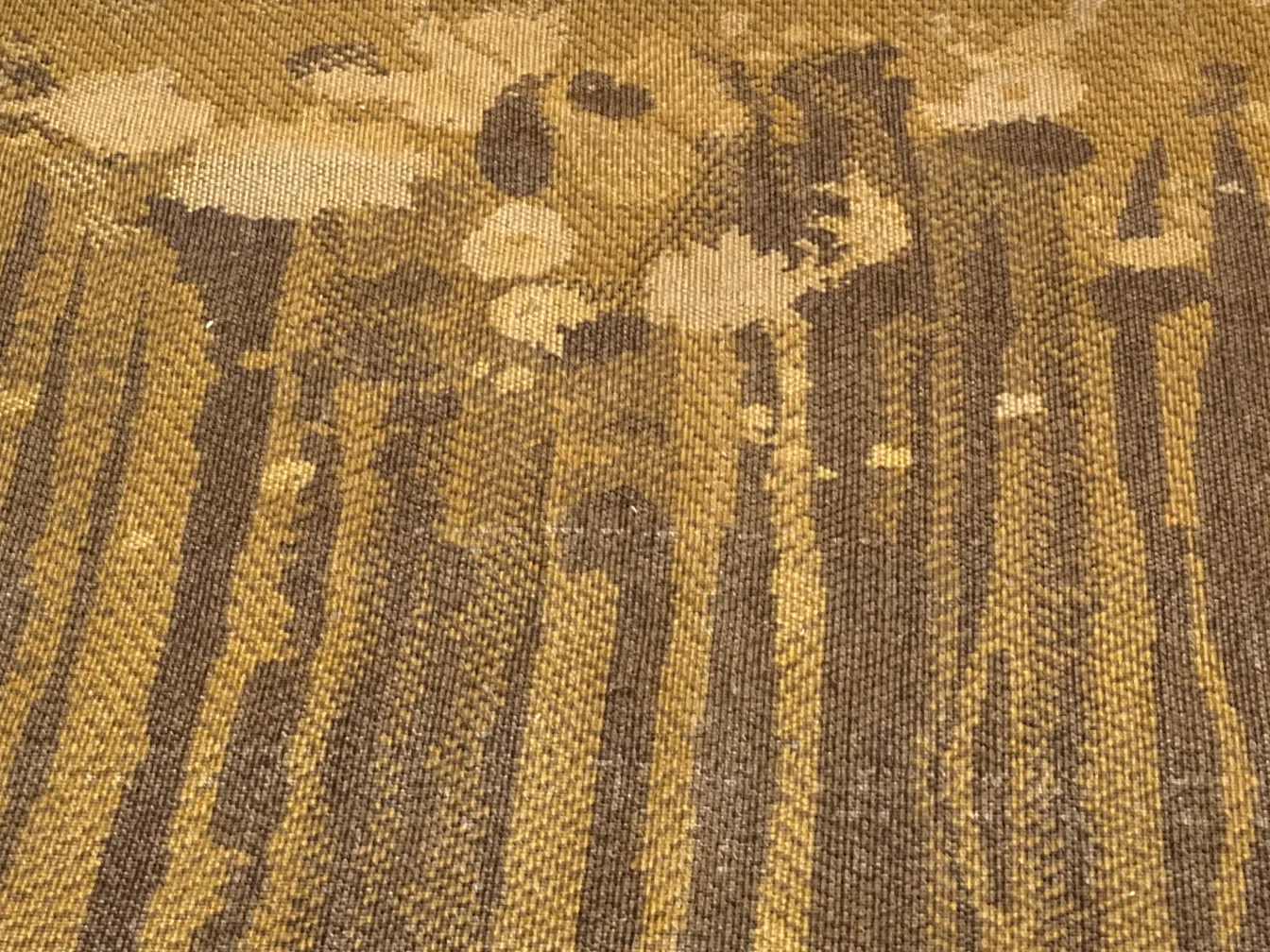 Tapis ancien avec des motifs naturels dans des tons bruns et dorés.