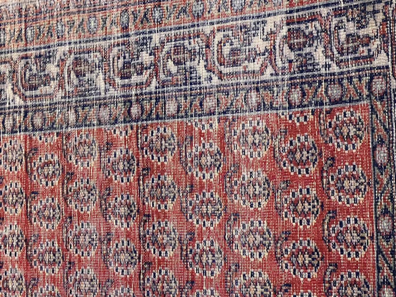 Tapis ancien avec un design floral en rouge et bleu.