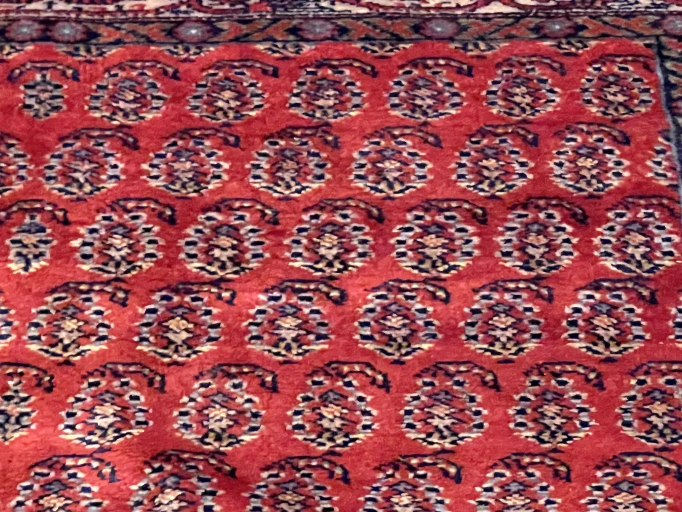 Alfombra antigua con diseño colorido, en un entorno acogedor.