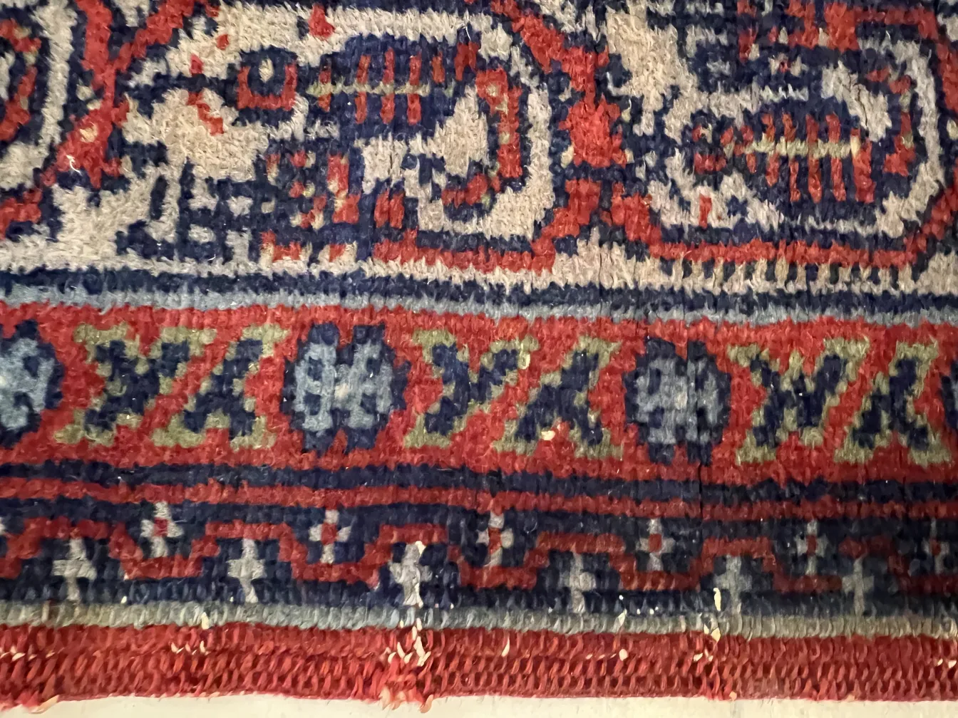 Antique carpet with vibrant patterns and colors in a cozy setting.