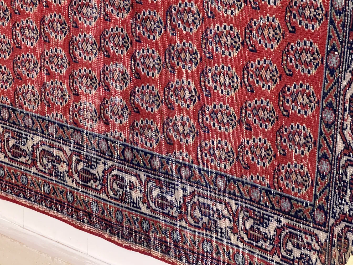 antique carpet featuring intricate patterns in red and blue tones, decorating a room