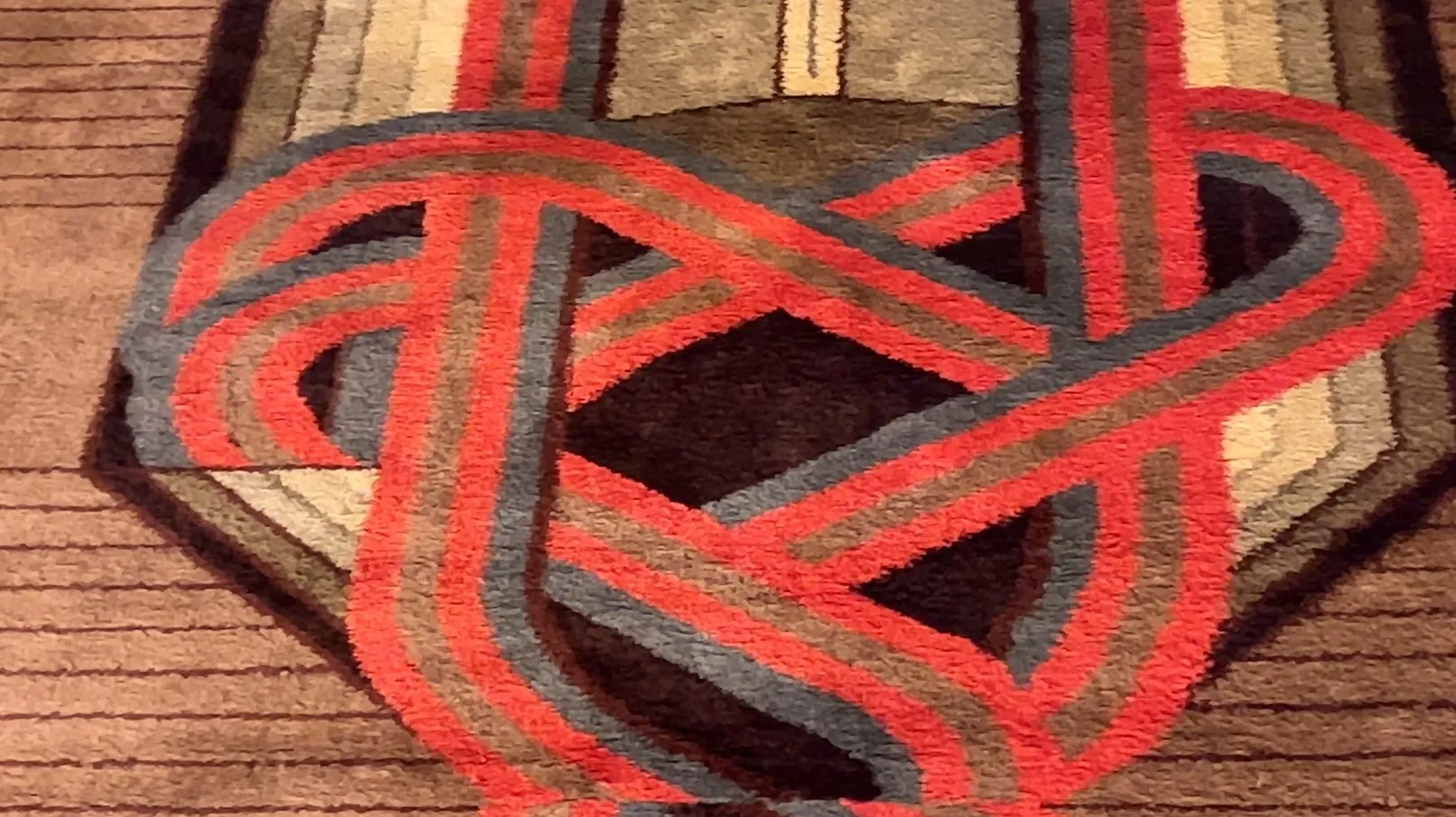 antique carpet featuring geometric design in gray and red hues