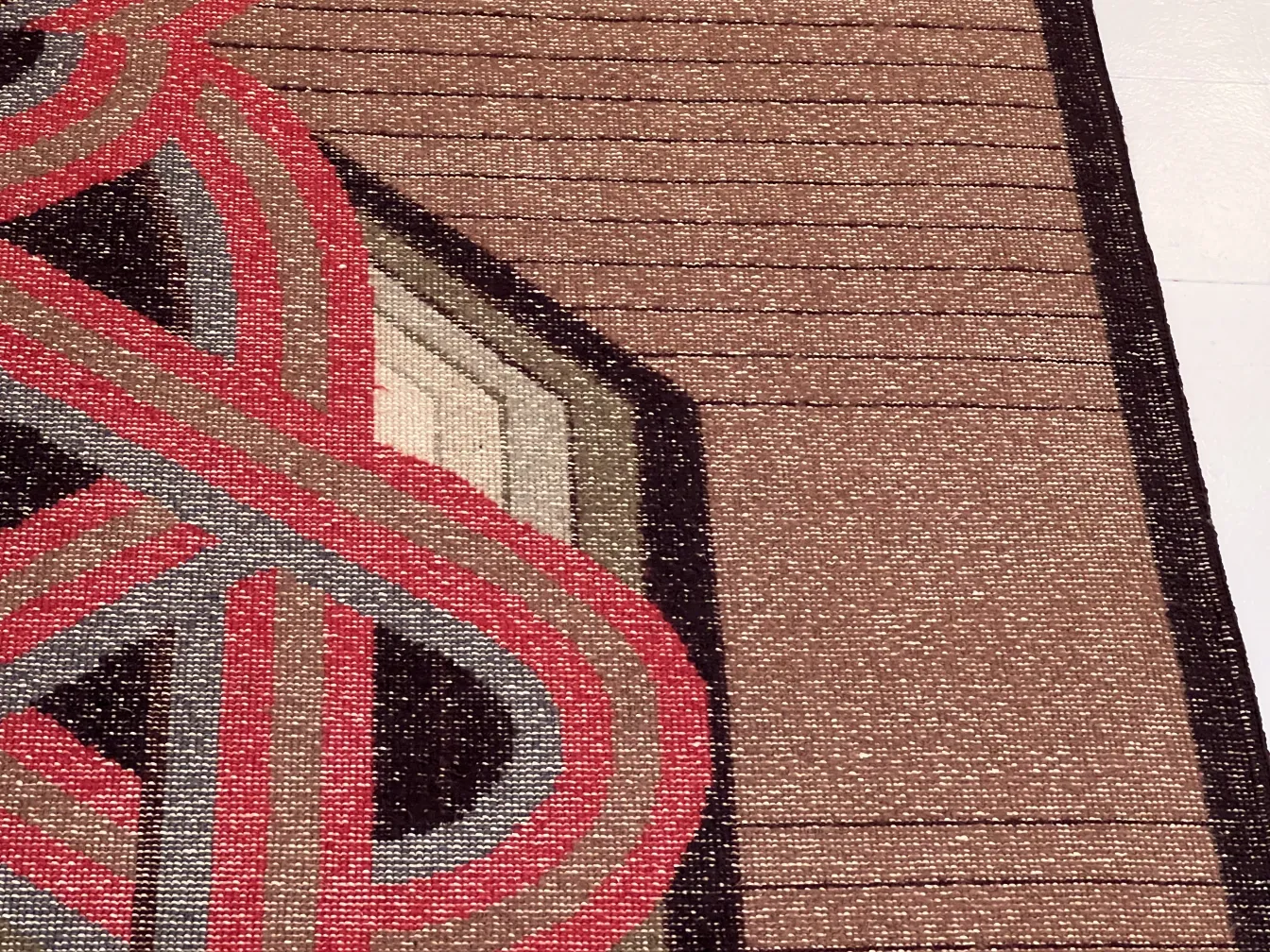 Tapis ancien avec des tons terreux et des formations géométriques.