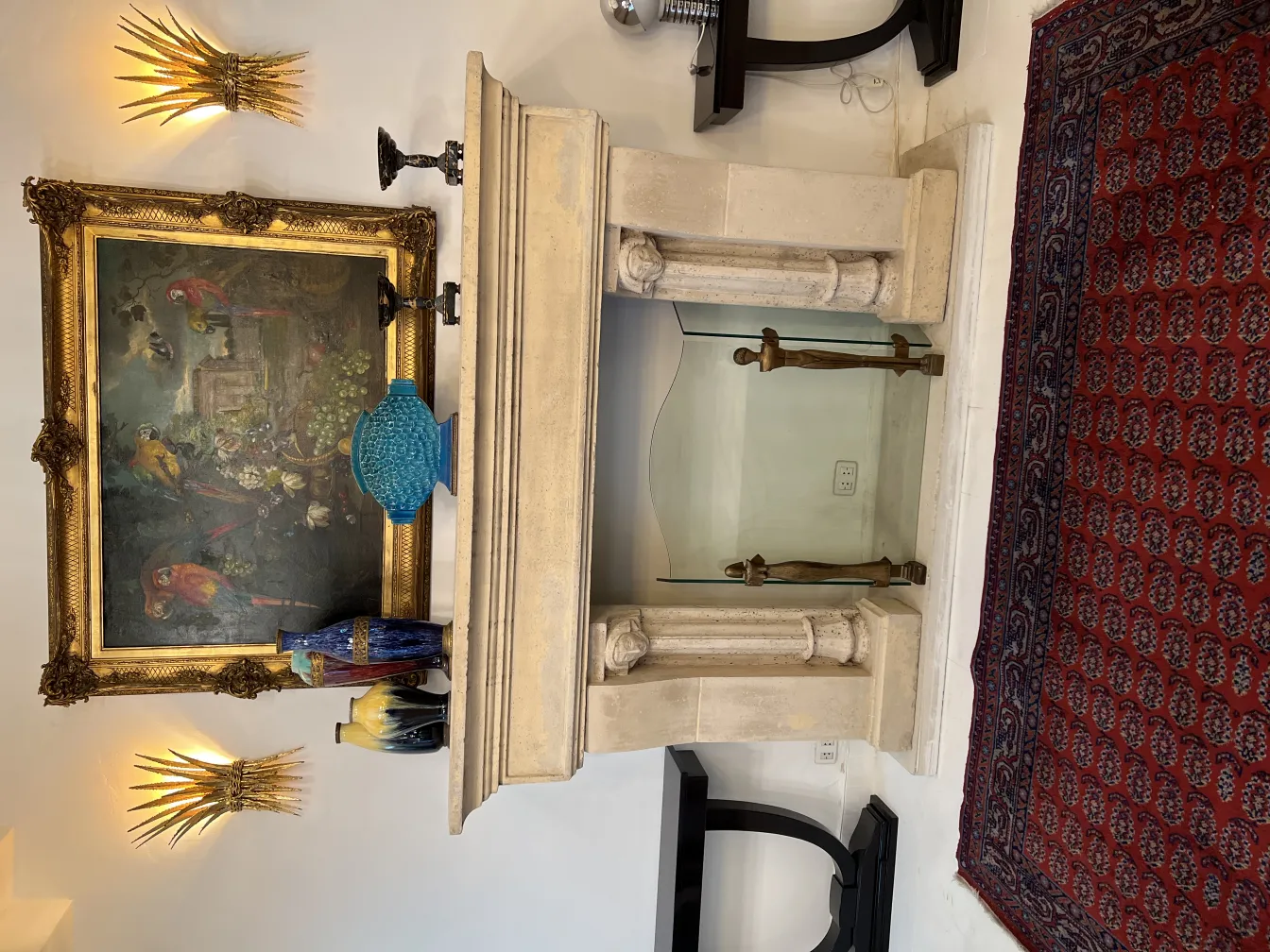 Tappeto antico decorativo rosso con motivi intricati accanto a un camino