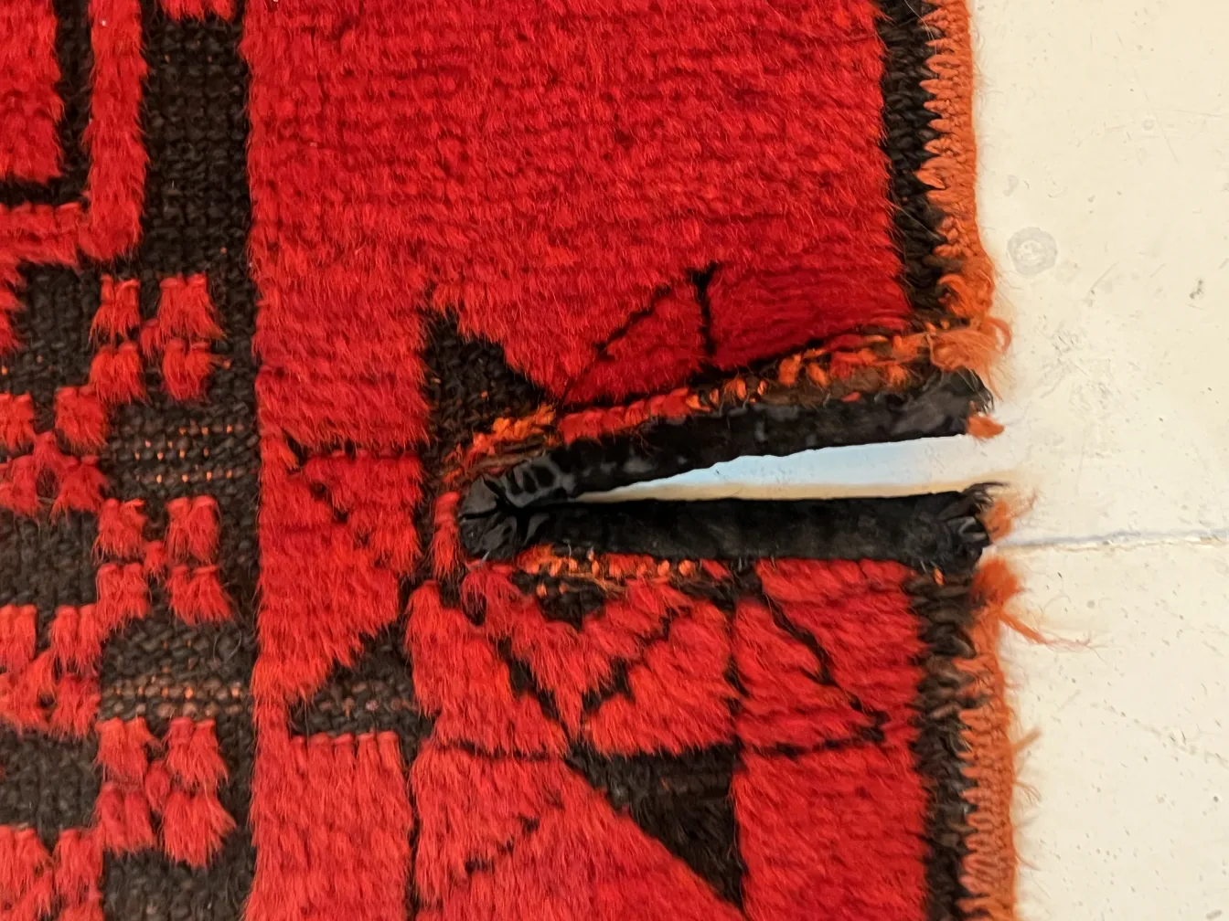 tapis ancien décoratif dans des tons rouges avec des détails noirs