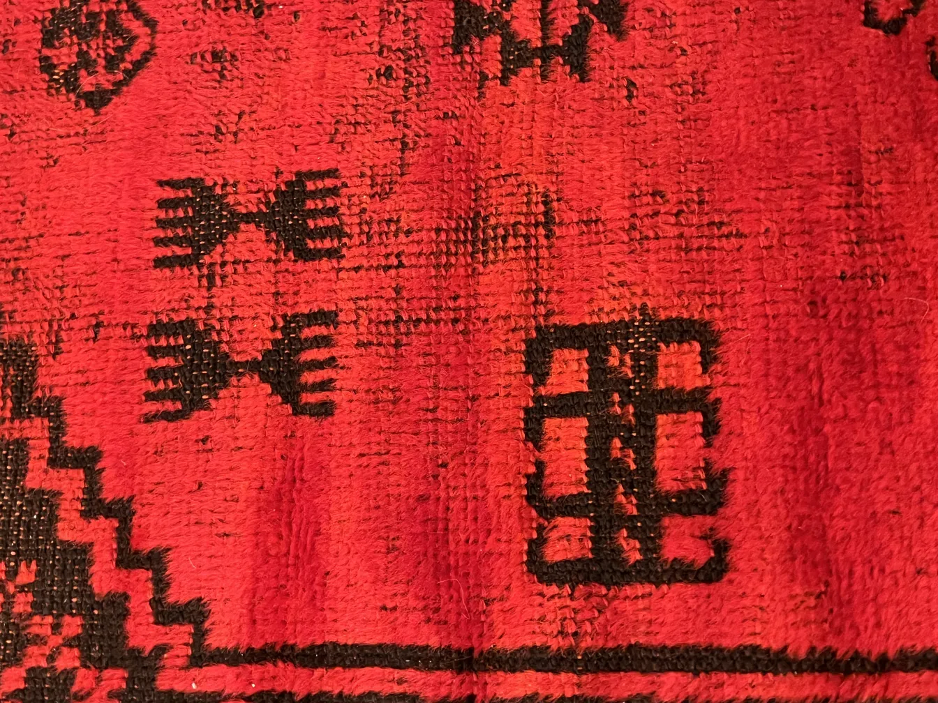 alfombra antigua de color rojo con diseños en negro