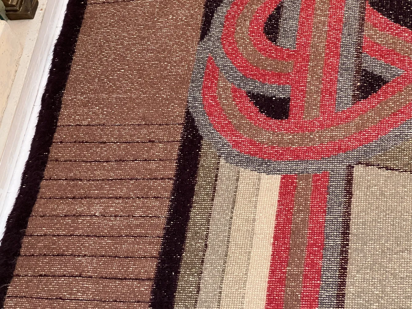 Antiker Teppich mit buntem Design in Braun- und Rottönen.