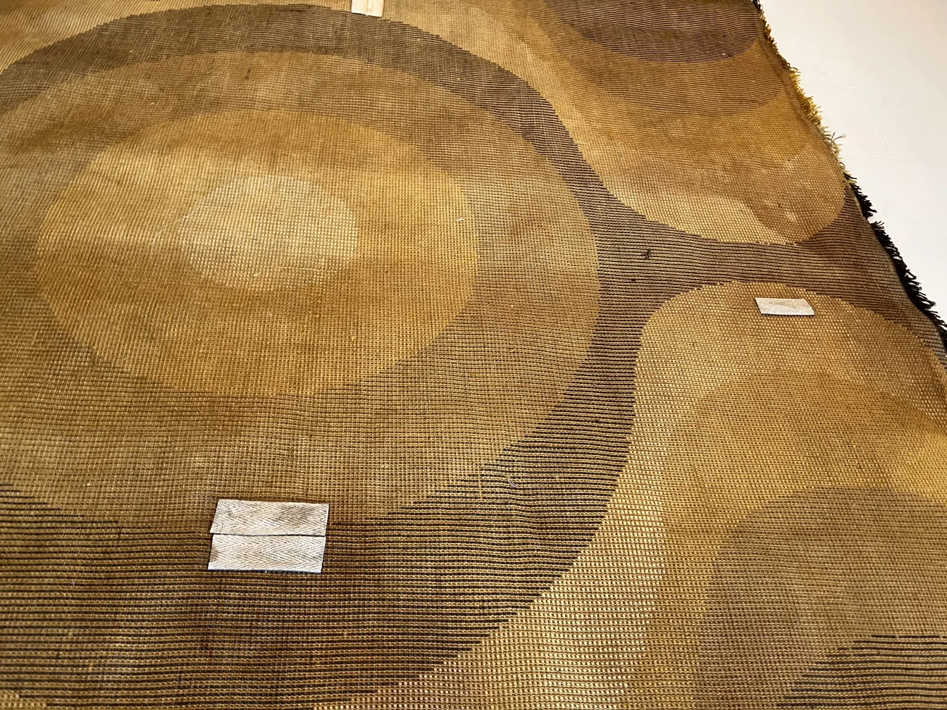 alfombra antigua con diseño de círculos marrones y amarillos, detalle visible