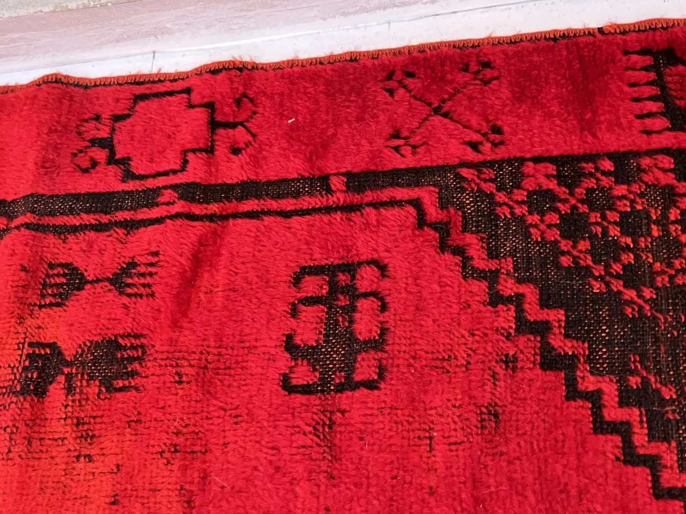 alfombra antigua roja con patrones negros en diseño