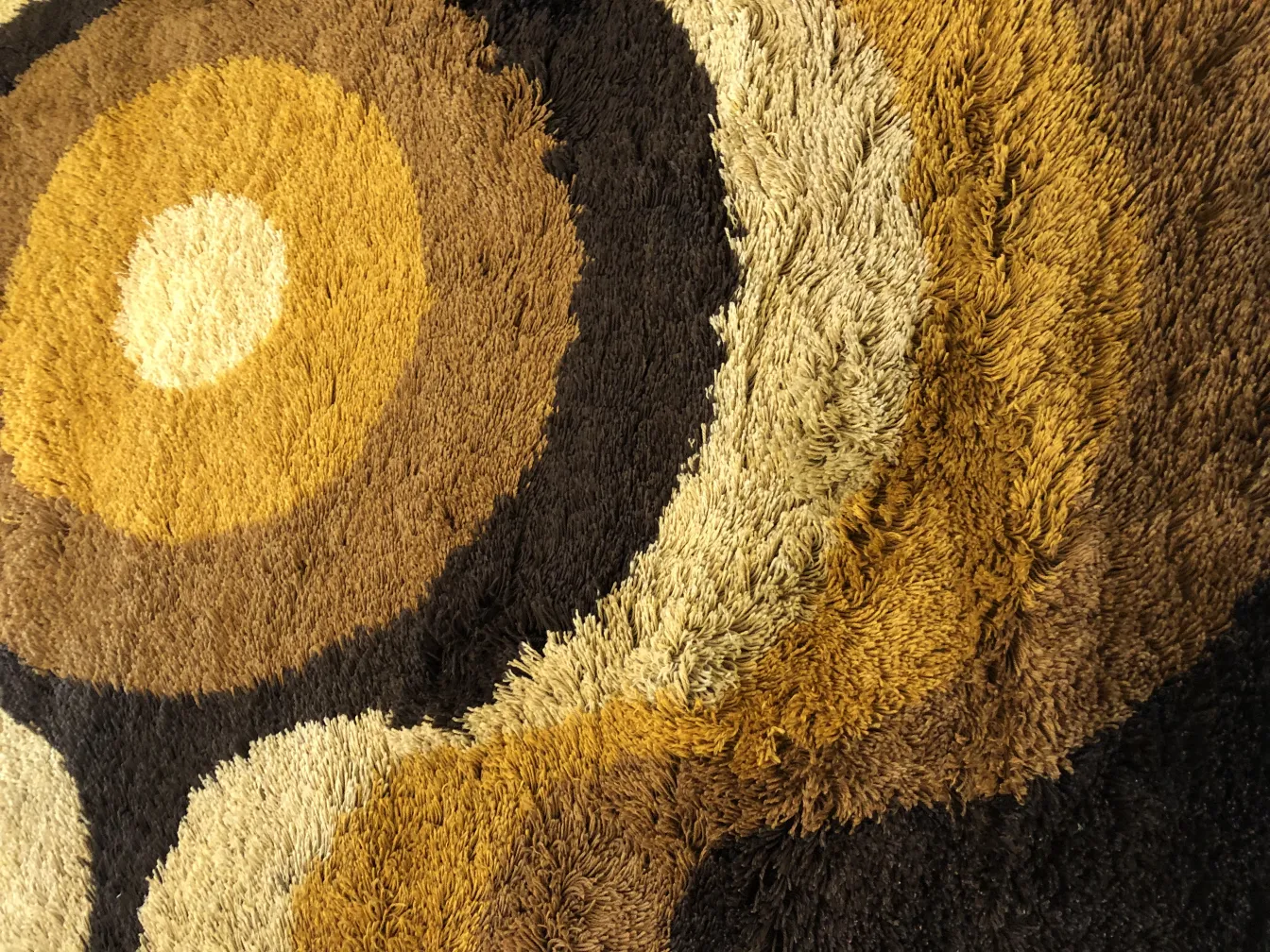 alfombra antigua con diseños geométricos en tonos marrones y beige