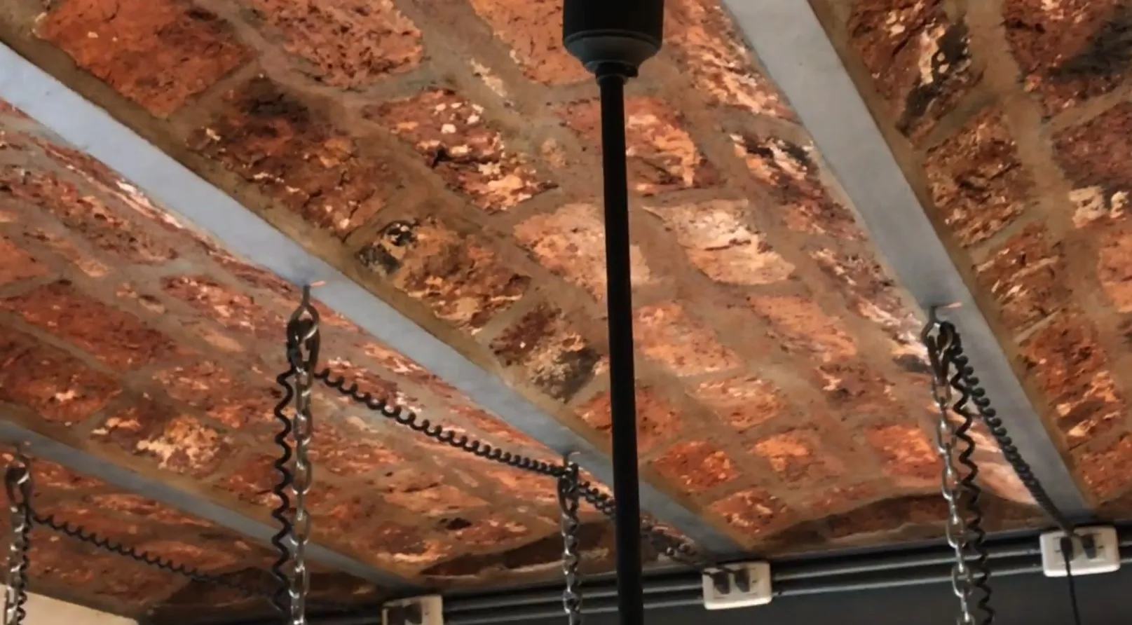 2 lampade a sospensione antiche appese in un ambiente accogliente con mattoni visibili