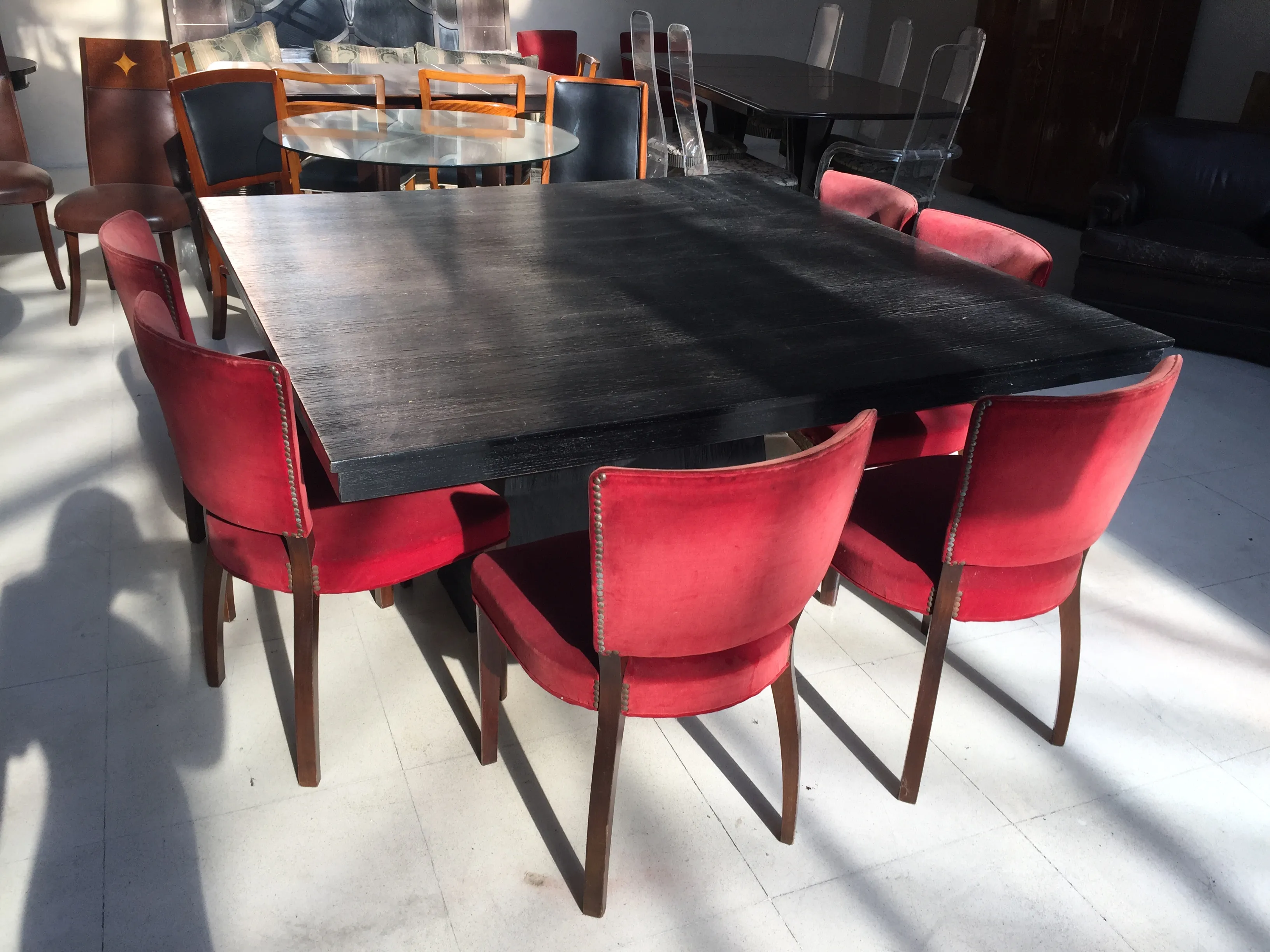 Table à manger ancienne pour 8 personnes avec des chaises rouges.