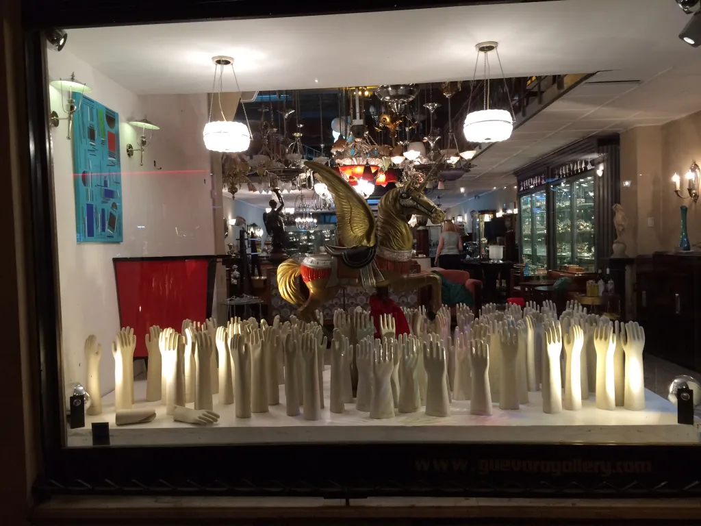 Deux lustres antiques illuminant une vitrine avec des objets artistiques.