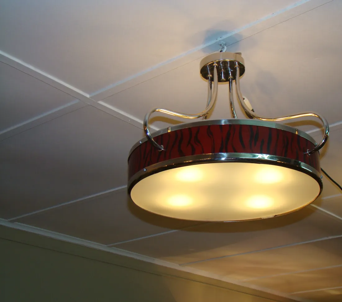 View of 2 antique hanging lamps with decorative design in a cozy setting.