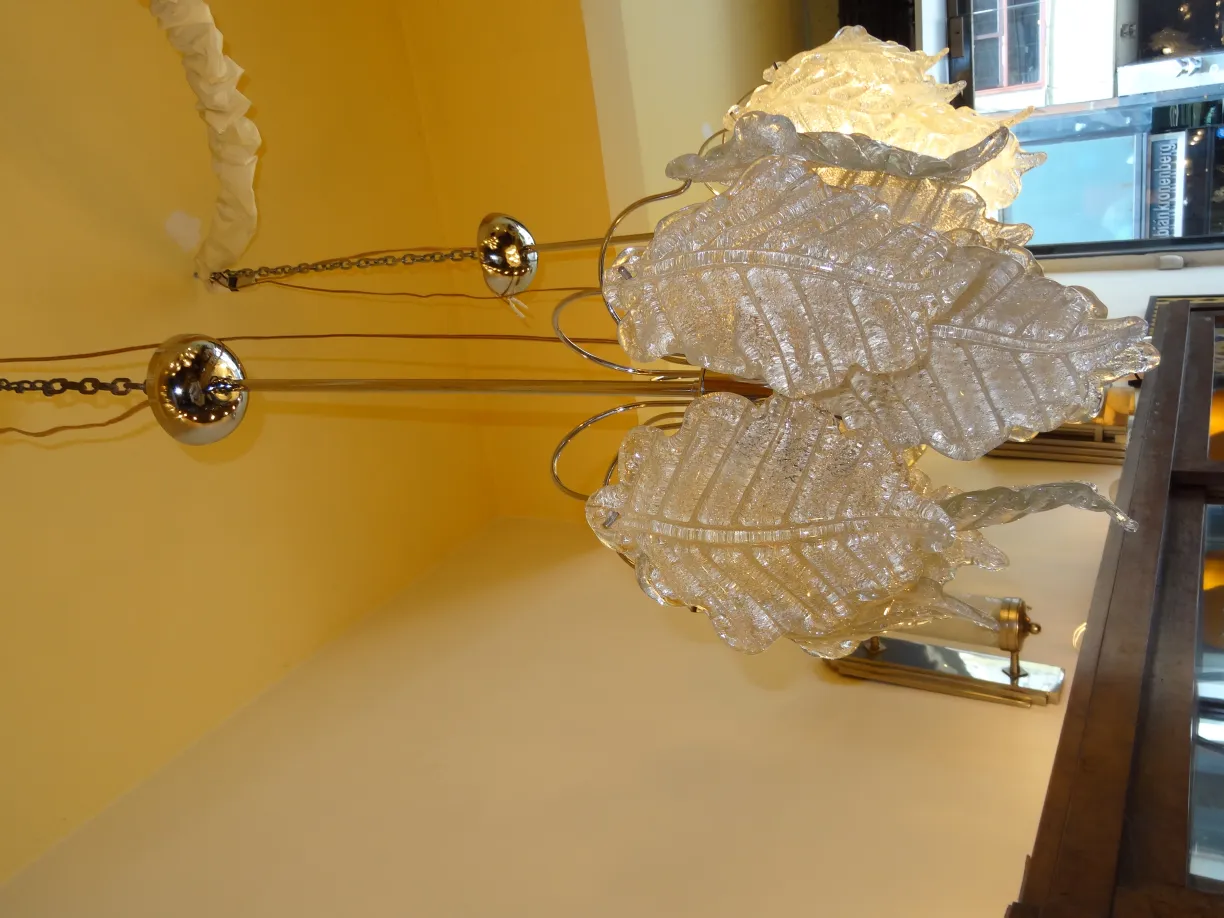 Duas lampadas de teto antigas com design de folhas brilhantes em um ambiente amarelo.